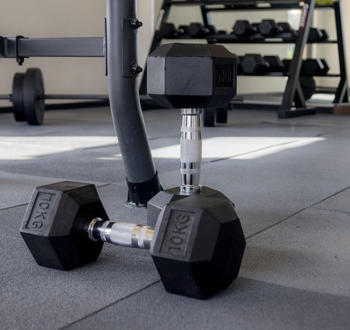 Black rubber tile flooring beneath dumbbells in a fitness space.