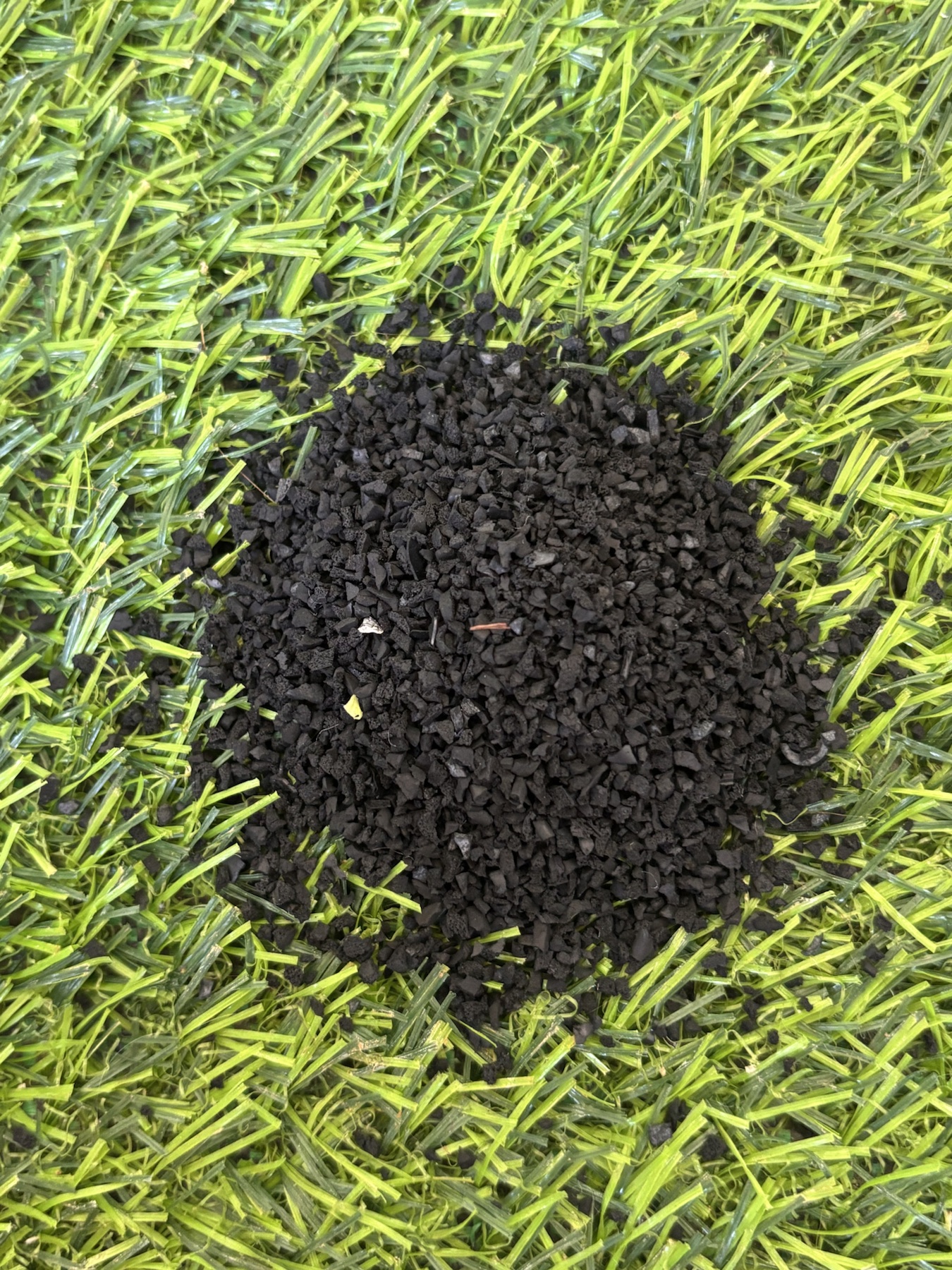 Fine black recycled rubber granules used in an artificial turf surface.