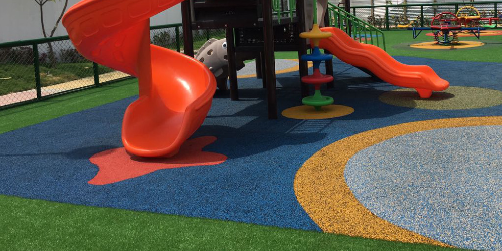 Playground with slides and a multicolor rubber safety surface.